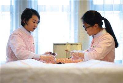 北京八宝山殡仪馆“青清女子工作室”整容师曲杰(右)和袁榕(左)正在为逝者整理遗容