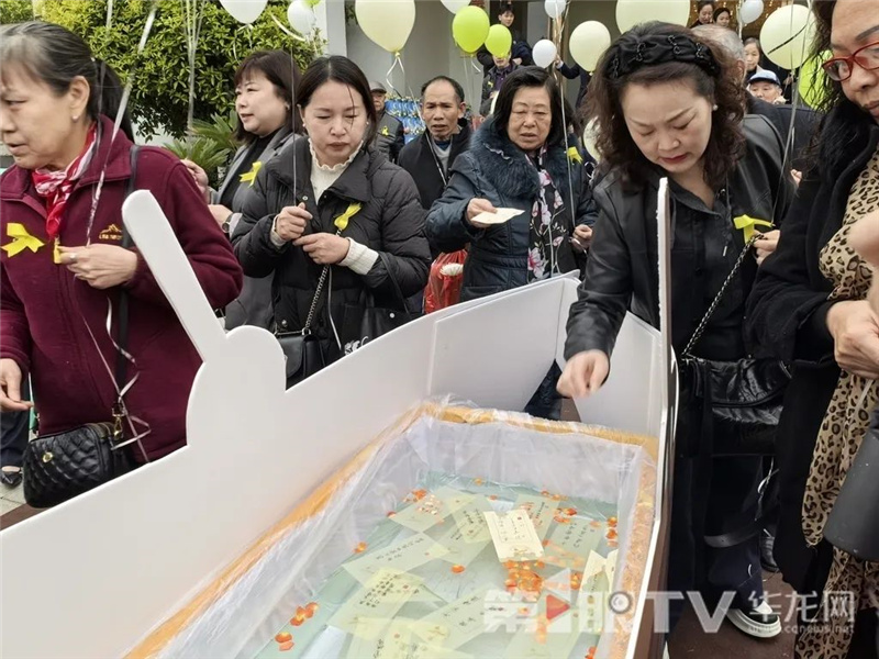 参与者将写满寄语的水溶纸放入“远航”的纸船。第1眼TV-华龙网 李舒 摄